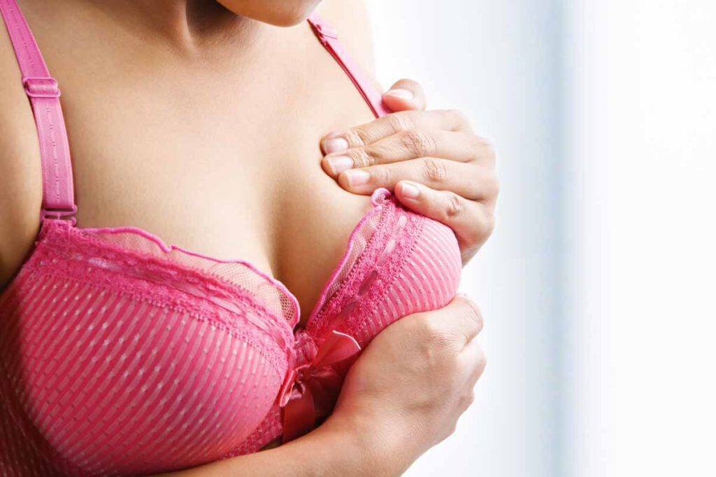 woman doing a breast examination to look for a lump in breast implant