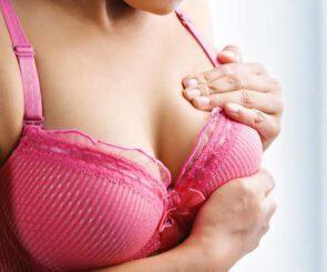 woman doing a breast examination to look for a lump after breast augmentation